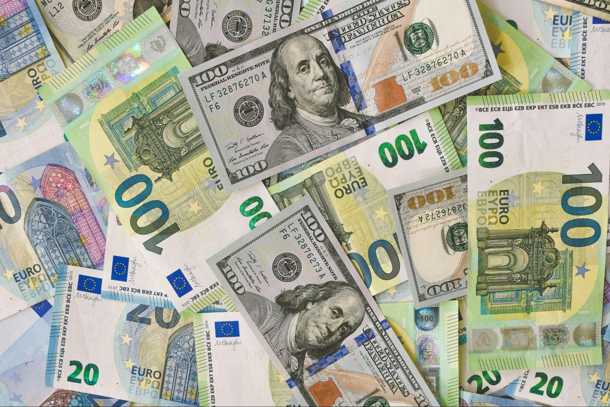 Scattered U.S. dollar and euro banknotes overlapping in a colorful display of mixed international currency