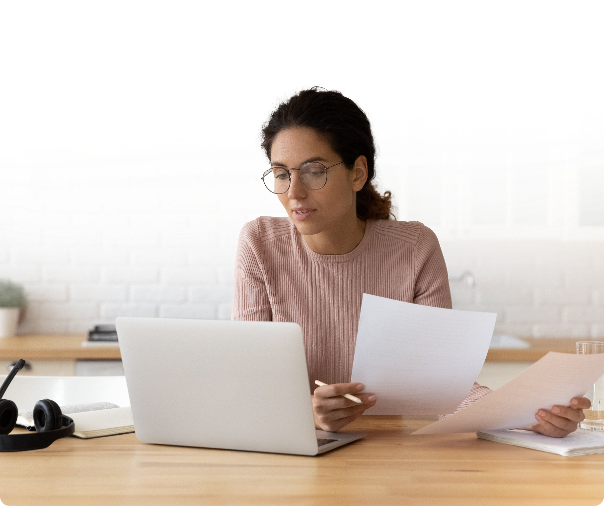 Woman sitting at desk with laptop comparing her paper notes