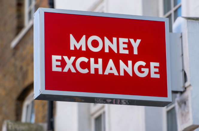 Red money exchange sign mounted outside a currency exchange storefront