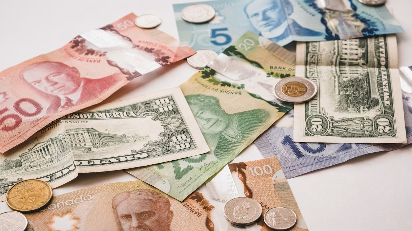 Multiple currencies, including U.S. dollars, Canadian dollars, and pesos, spread across a tabletop
