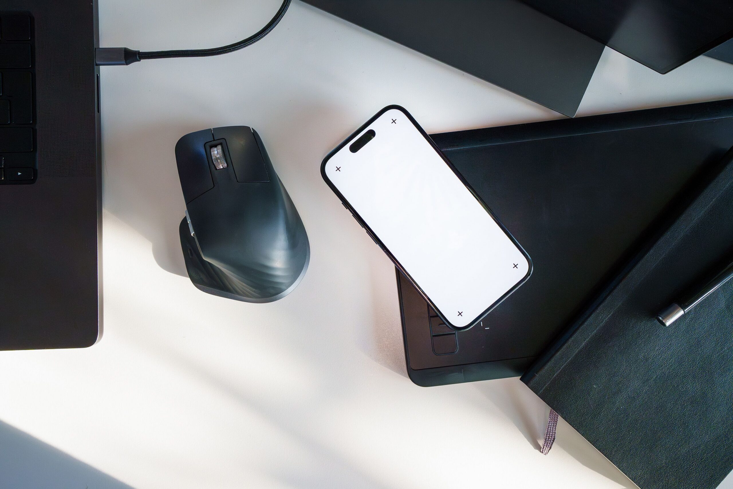A phone on a wooden desk showing a plain confirmation screen, a notebook and pen beside it, no legible personal details